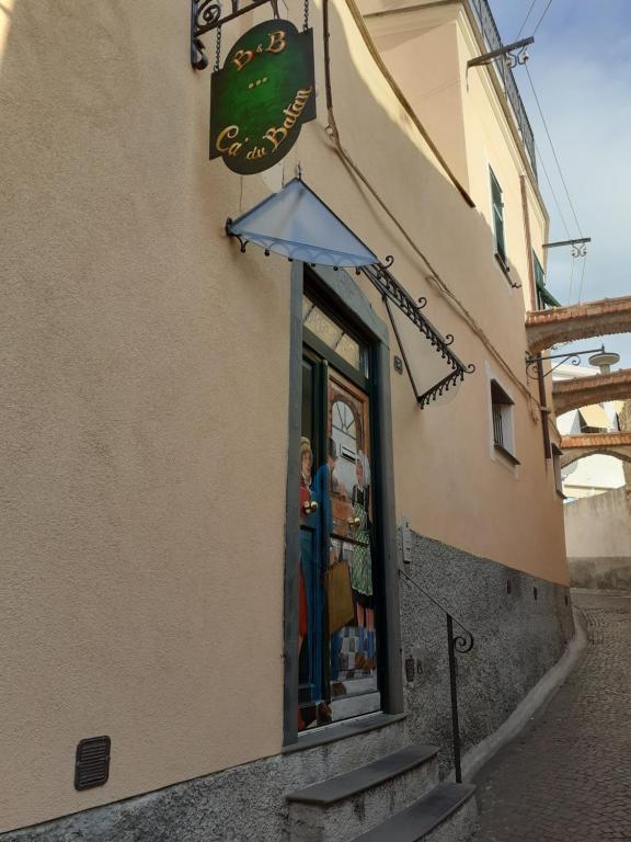 une femme debout dans une fenêtre de magasin avec un parapluie dans l'établissement Ca' Du Batan, à Spotorno