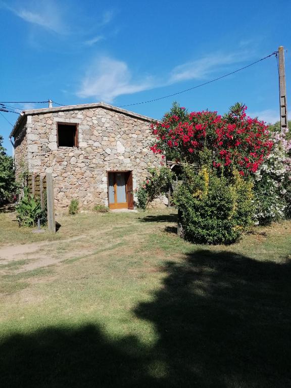 a stone building with red flowers in front of it at Sarrola-Carcopino Gîte en Pierre in Sarrola-Carcopino