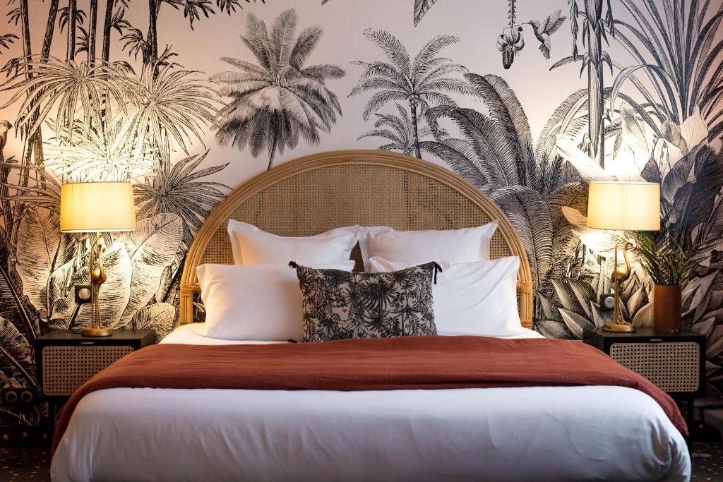 a bedroom with a large bed with palm wallpaper at Hôtel Restaurant Vaillant proche Europapark Rulantica in Sélestat