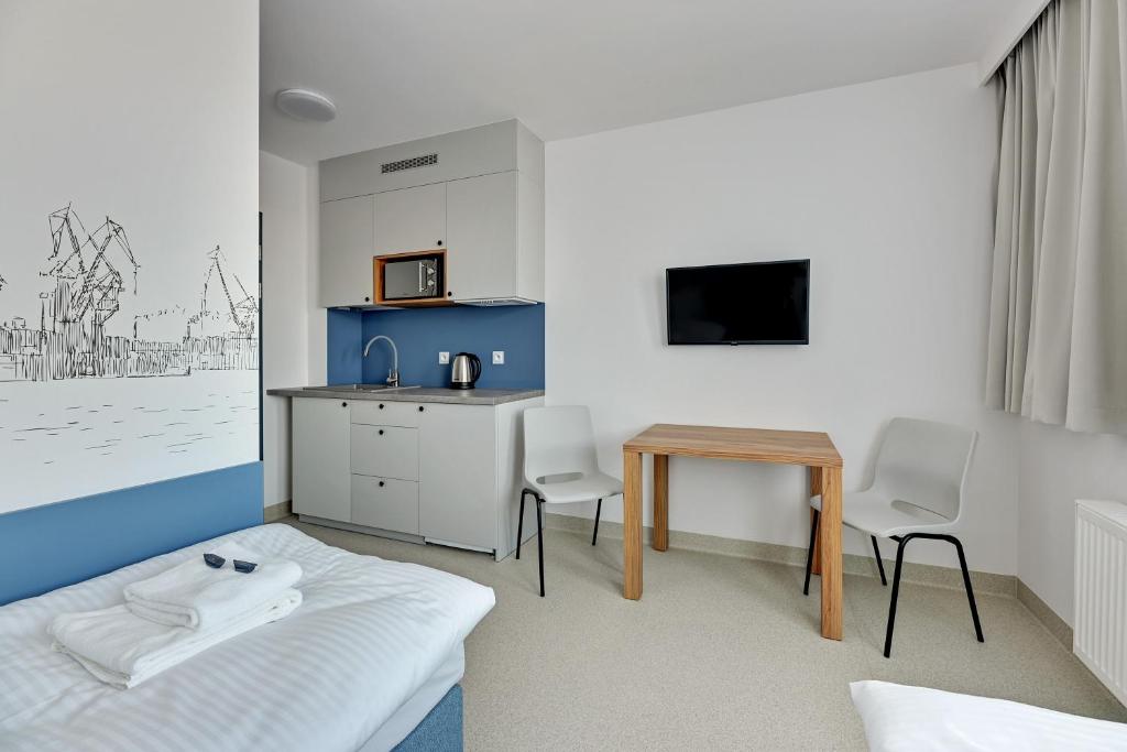 Pokój z łóżkiem, stołem i kuchenką mikrofalową w obiekcie Apartgdynia w mieście Gdynia