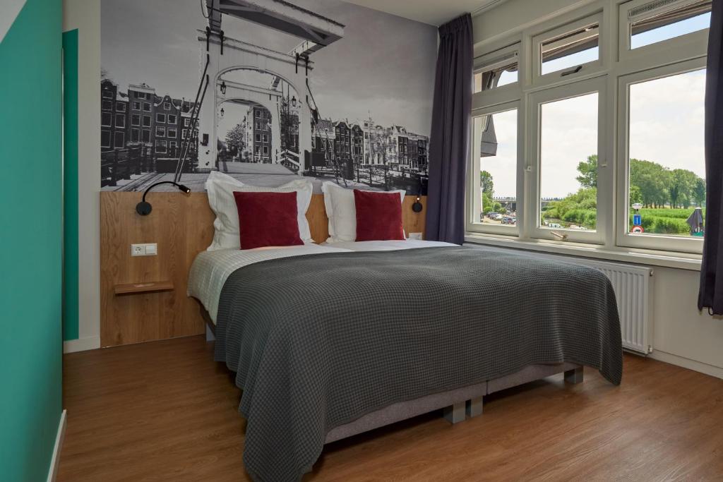 een slaapkamer met een groot bed met rode kussens bij Hotel VILLA GROET in Avenhorn