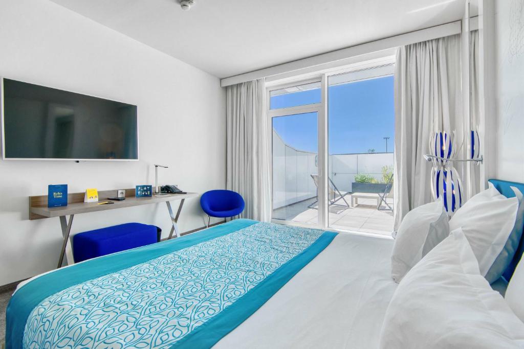 a bedroom with a bed and a view of the ocean at Golden Tulip Marseille Euromed in Marseille