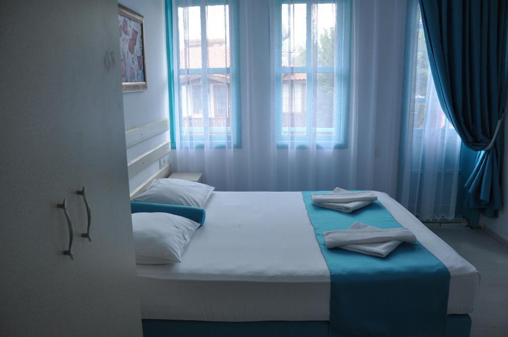 a bedroom with a bed with blue sheets and windows at Hotel Nisa in Kas
