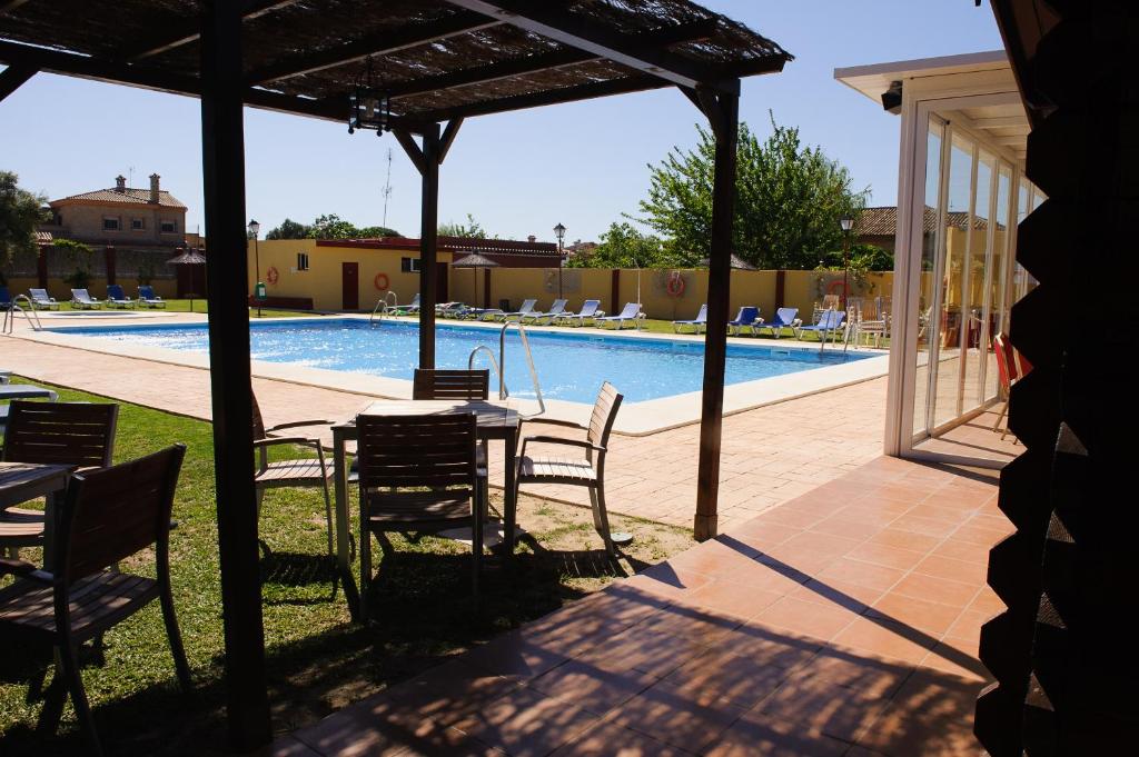 a patio with a table and chairs next to a swimming pool at Hotel Dunas Puerto in El Puerto de Santa María