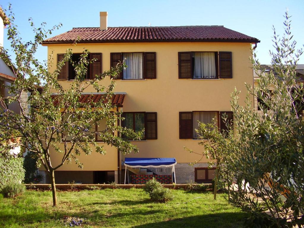 a yellow house with a blue umbrella in a yard at Apartment Borik in Pula