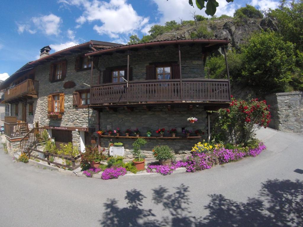 a house with a balcony and flowers in front of it at B&B La Mandorla in Quart