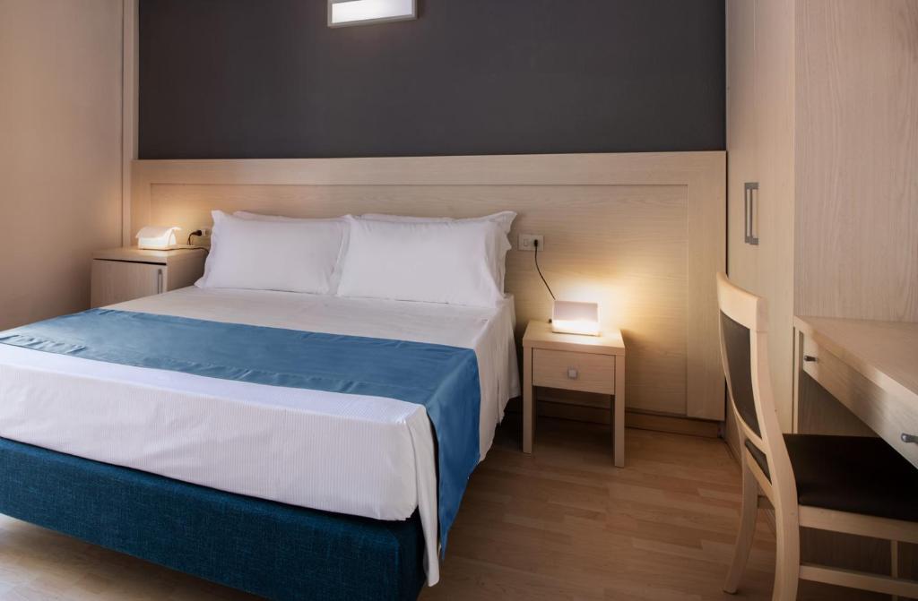 a bedroom with a bed and a desk with two lamps at Hotel Baia Imperiale in Campo nell'Elba