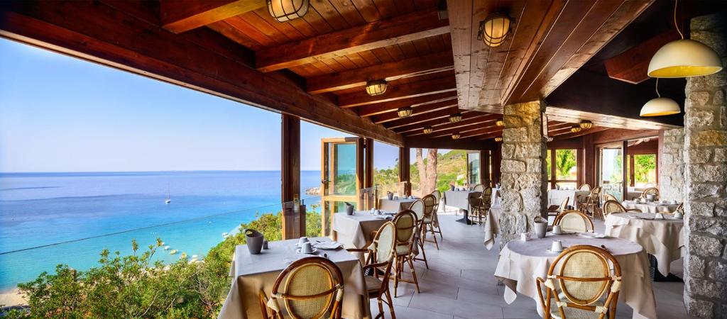 a restaurant with tables and chairs and the ocean at Hotel Baia Imperiale in Campo nell'Elba