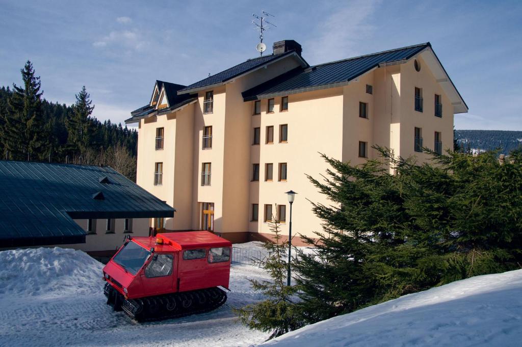 un véhicule rouge garé devant un bâtiment dans l'établissement Apartmán ve SkiResortu Poustevník - Pec pod Sněžkou, à Pec pod Sněžkou