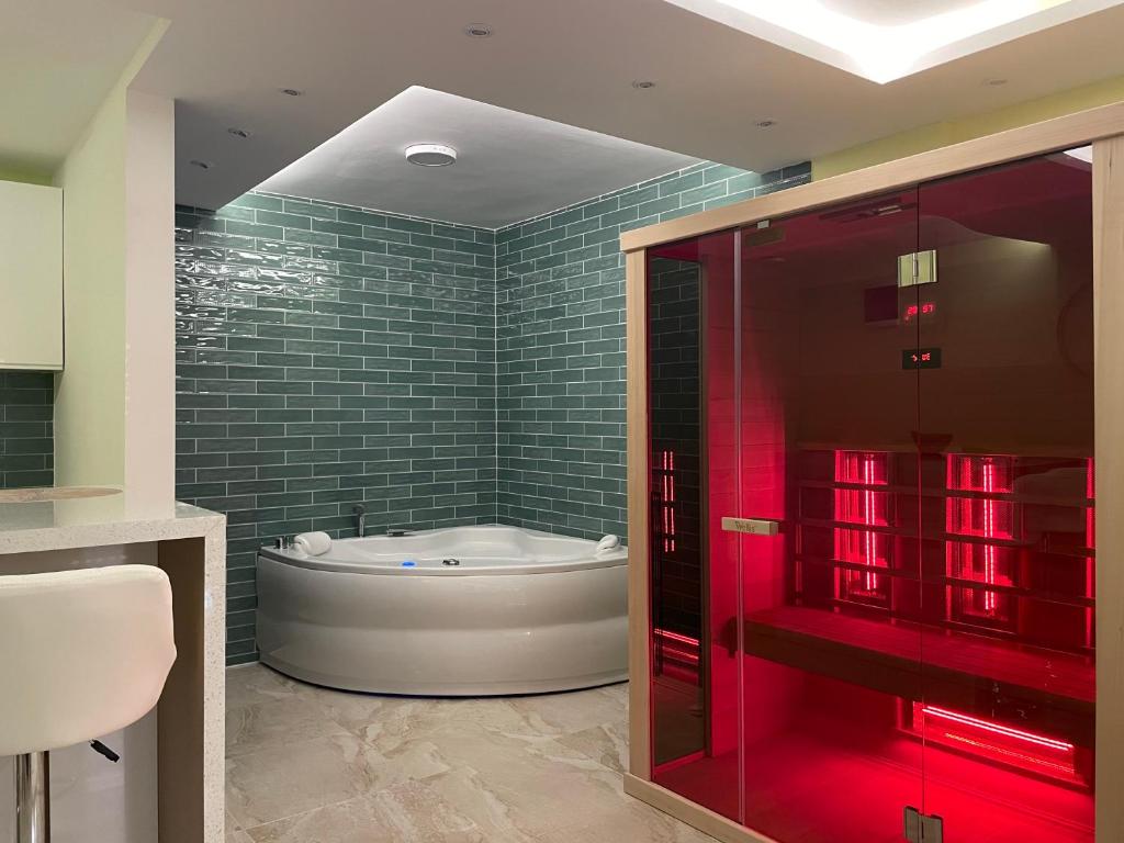 ein Bad mit einer Badewanne und einer Dusche mit roten Lichtern in der Unterkunft Spa apartman Sobhe in Vrnjačka Banja