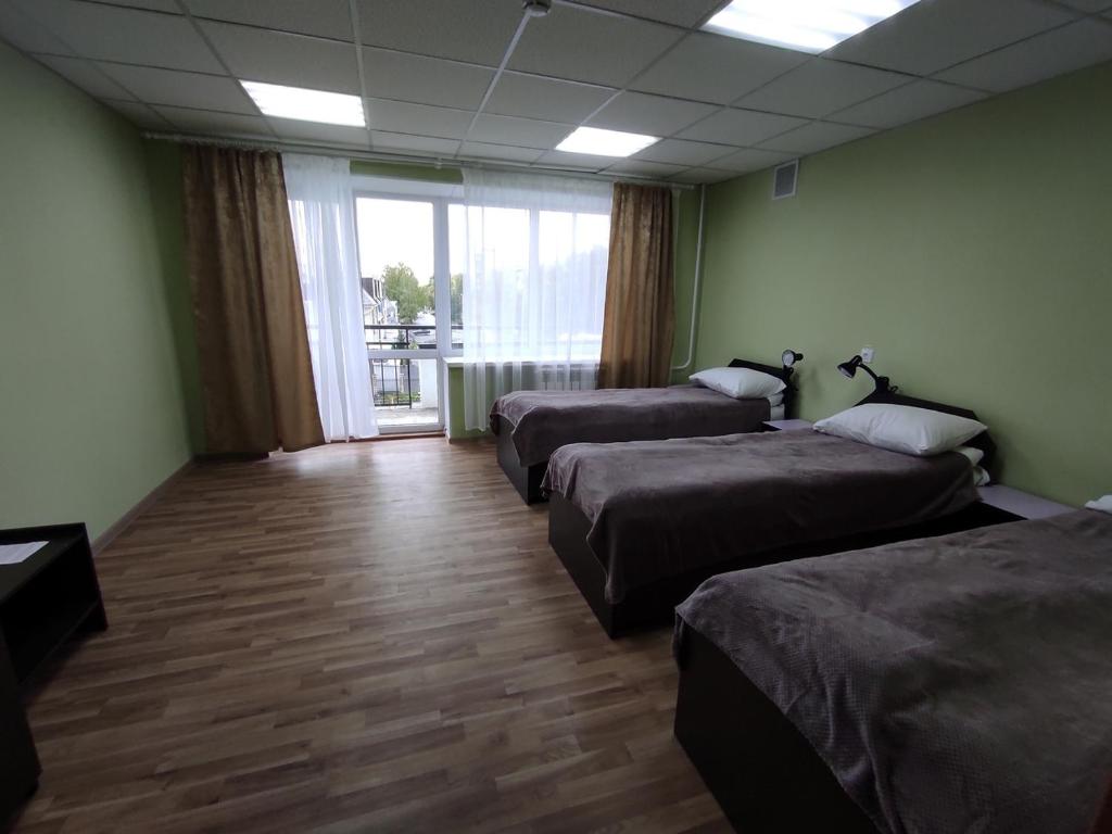 een kamer met 3 bedden en een groot raam bij Комплекс центр развития туризма in Zlato-oest