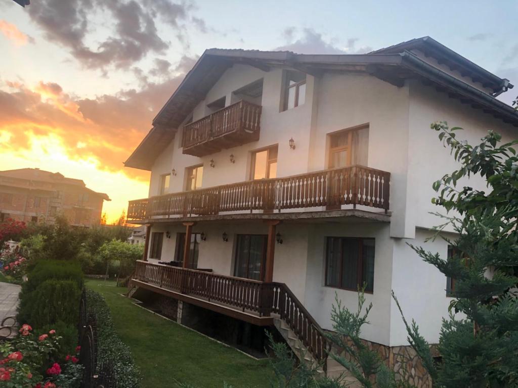 a white house with balconies and a sunset at Guest House Stoyanov in Bansko