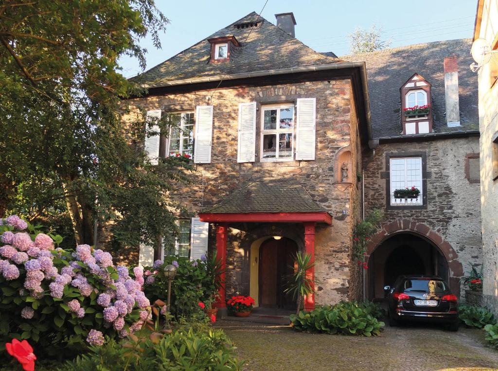 ein altes Steinhaus mit einem davor geparkt in der Unterkunft Pension Marienhof in Kobern-Gondorf