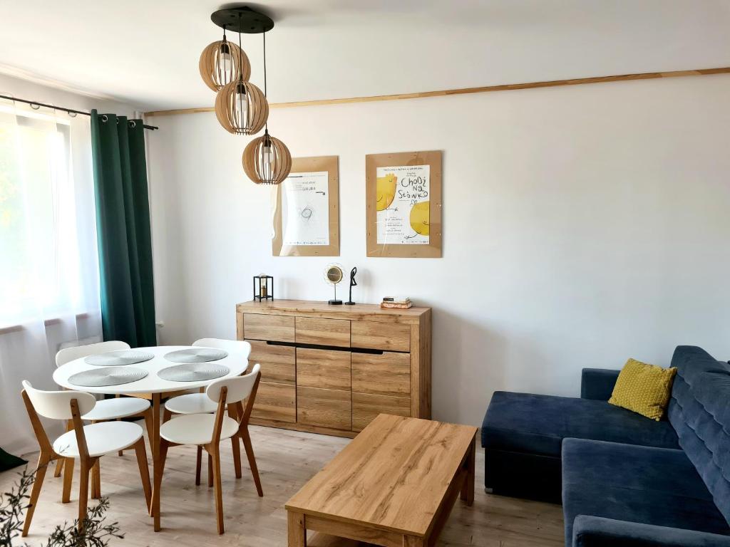 een woonkamer met een tafel en een blauwe bank bij Apartament Wałbrzych / Piaskowa Góra in Wałbrzych