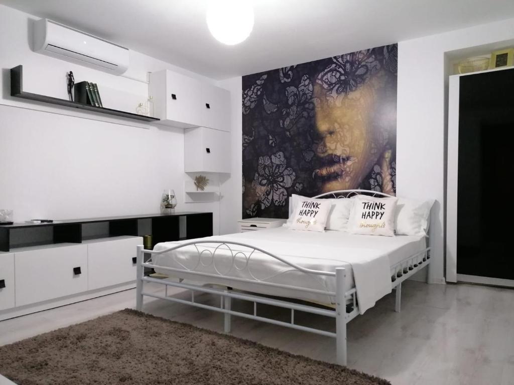 a white bedroom with a bed and a painting on the wall at Alexandra House in Costinesti