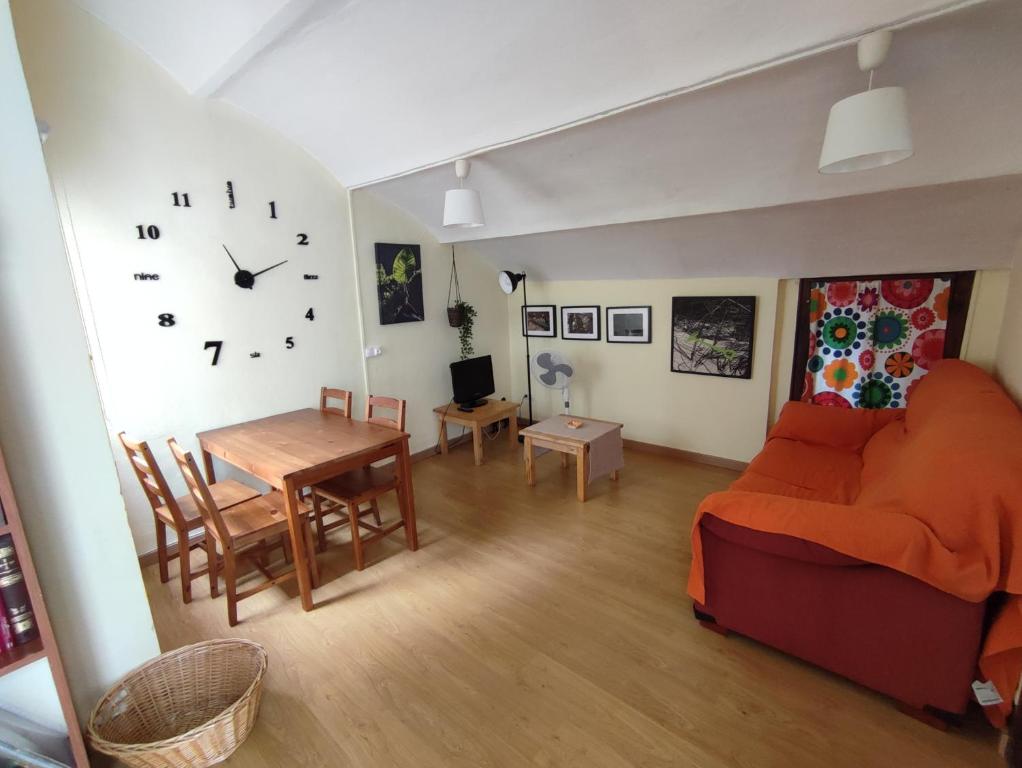 sala de estar con sofá, mesa y reloj en 202A Ático con encanto - Centro de Villaviciosa, en Villaviciosa