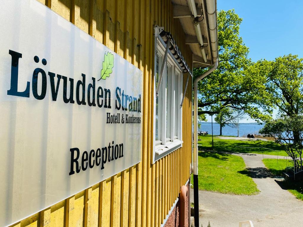 ein Schild an der Seite eines gelben Gebäudes in der Unterkunft Lövudden Strand in Västerås