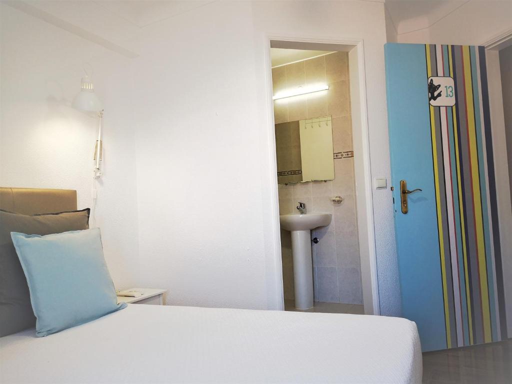 a hotel room with a white bed and white walls at The Bulldog Inn - Duna Parque Group in Vila Nova de Milfontes