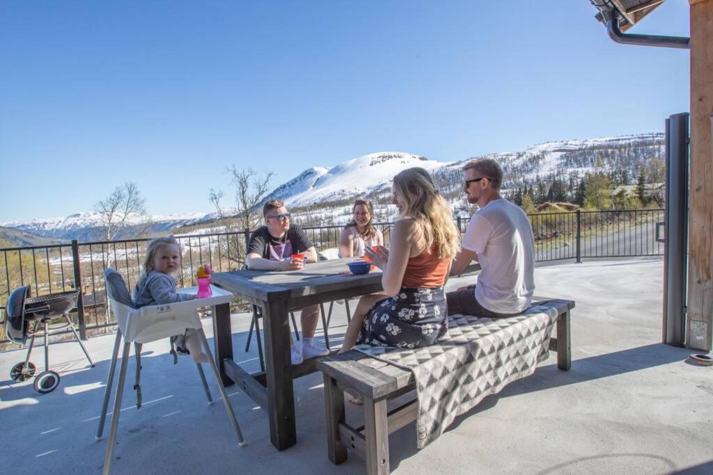 een groep mensen die aan een tafel op een patio zitten bij Fosskamben 1 Moderne hytte ikkje langt frå Sogndal in Sogndal