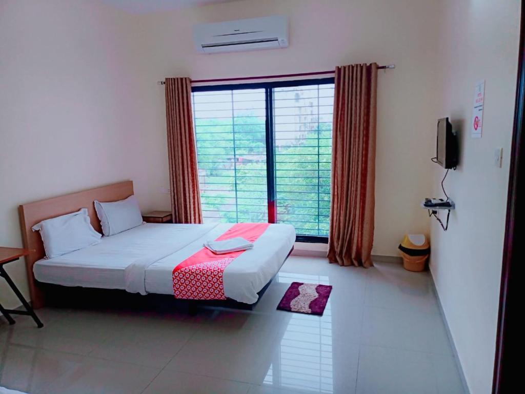 a bedroom with a bed and a large window at Hotel Relax Inn in Nagpur