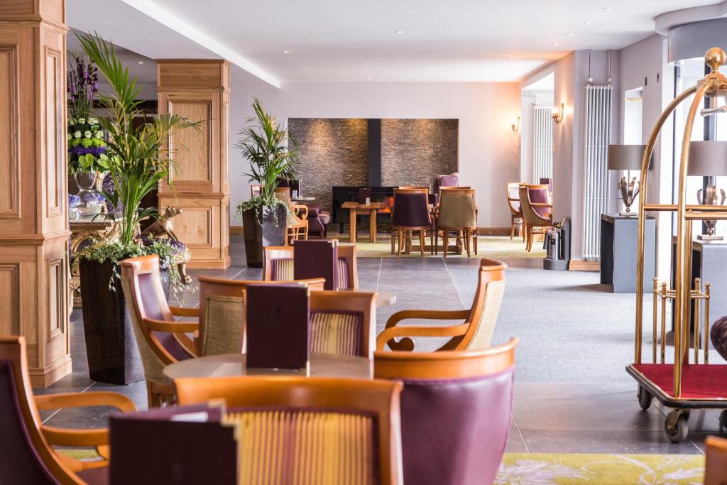 a restaurant with tables and chairs in a lobby at Ballygally Castle in Larne