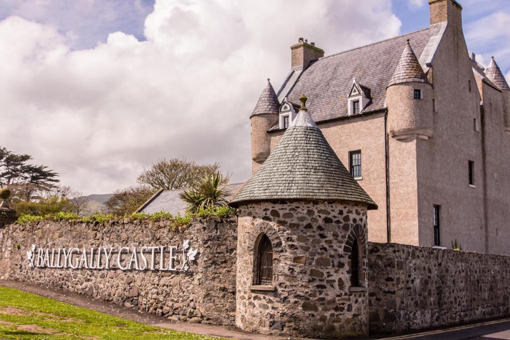 a building with a stone wall next to a fence at Ballygally Castle in Larne