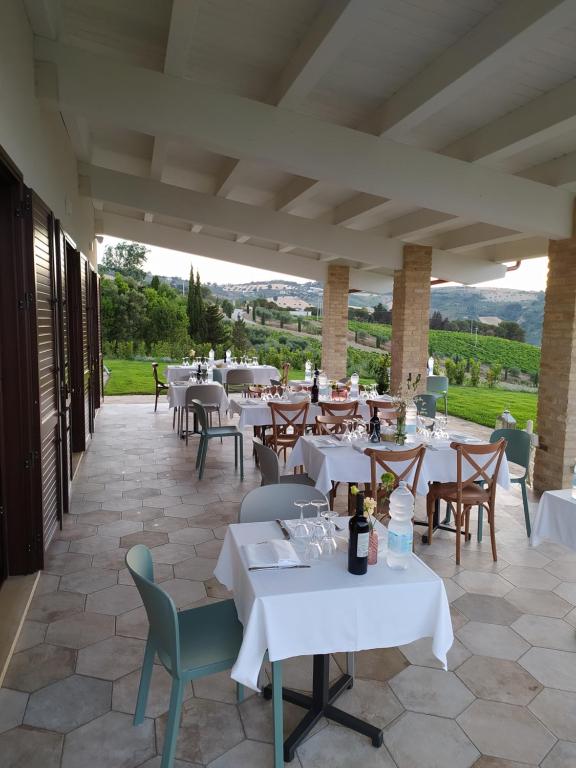 un restaurante con mesas blancas y sillas en un patio en Casale Adriatico B&B en Pineto