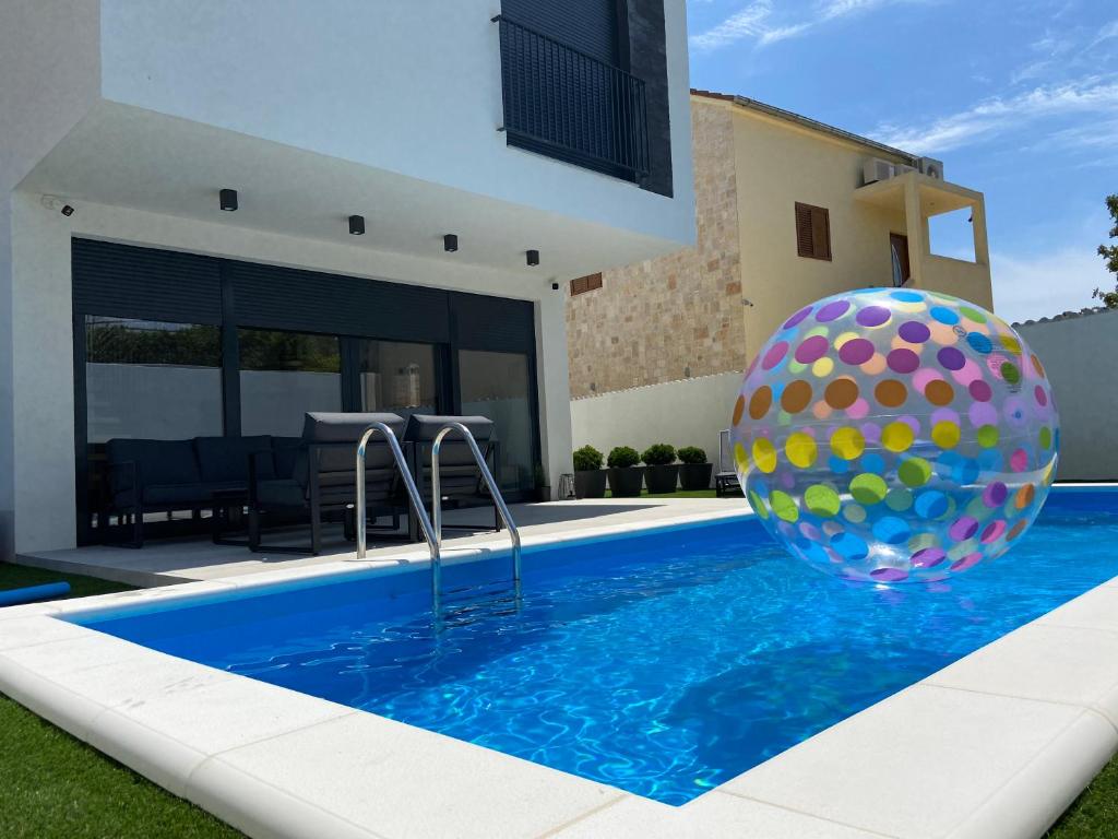 una piscina con una gran pelota frente a una casa en Murter - Jezera Luxury Apartments, en Jezera