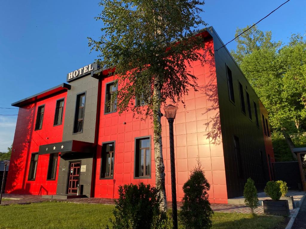 a red building with a tree in front of it at Гостиница Бумеранг in Vladikavkaz