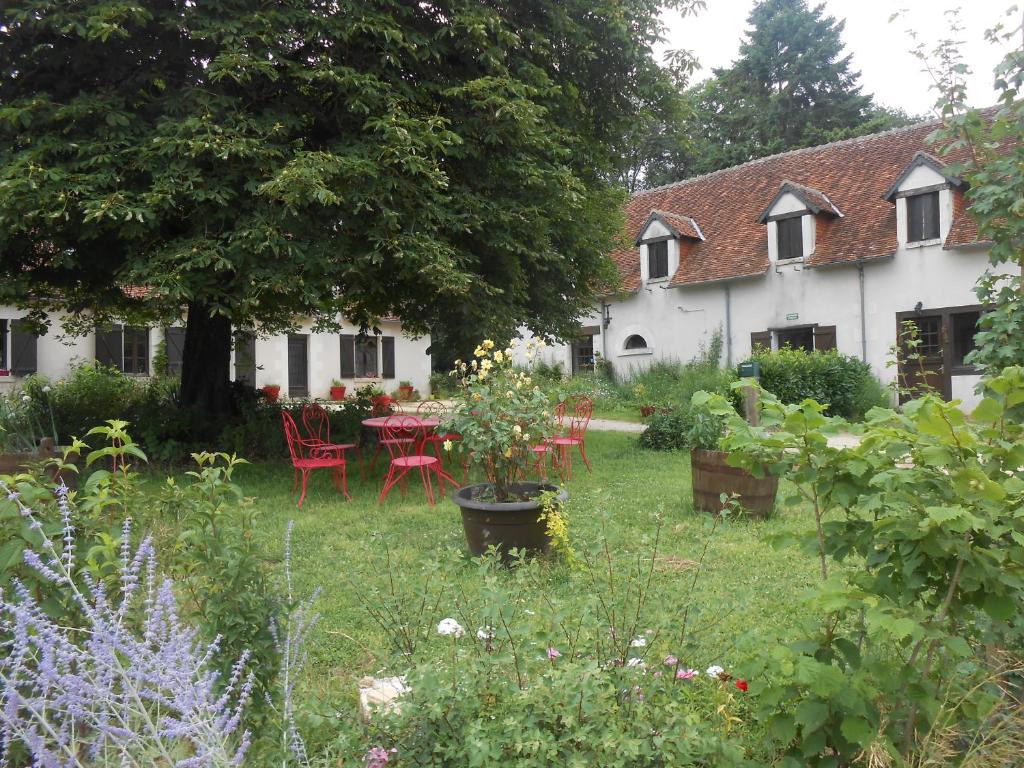 a garden in front of a white house with a table and chairs at B&B La Ferme des Bordes in Pontlevoy