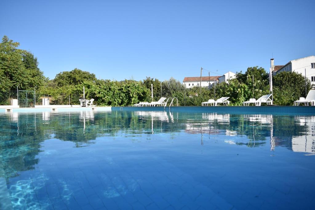 una gran piscina de agua con mesas y sillas en MemSoares Country House, en Castelo de Vide