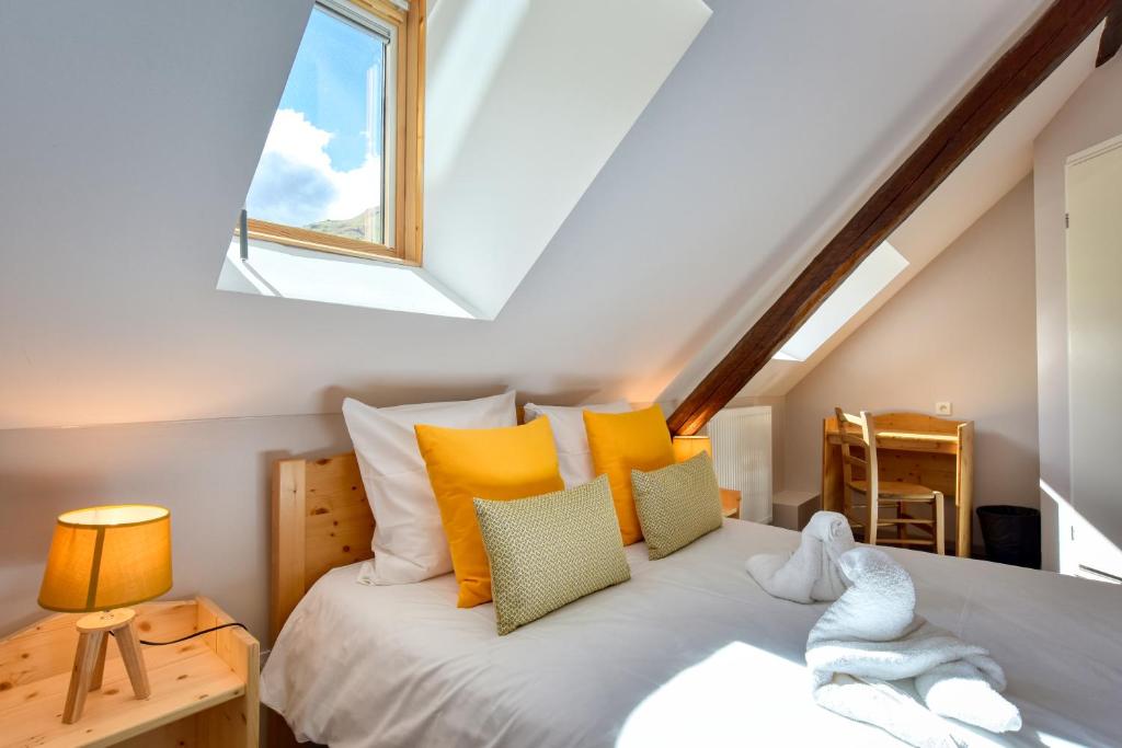 sypialnia z łóżkiem z żółtymi poduszkami i oknem w obiekcie Hôtel Les Essarts, USSIM Vacances w mieście Valloire