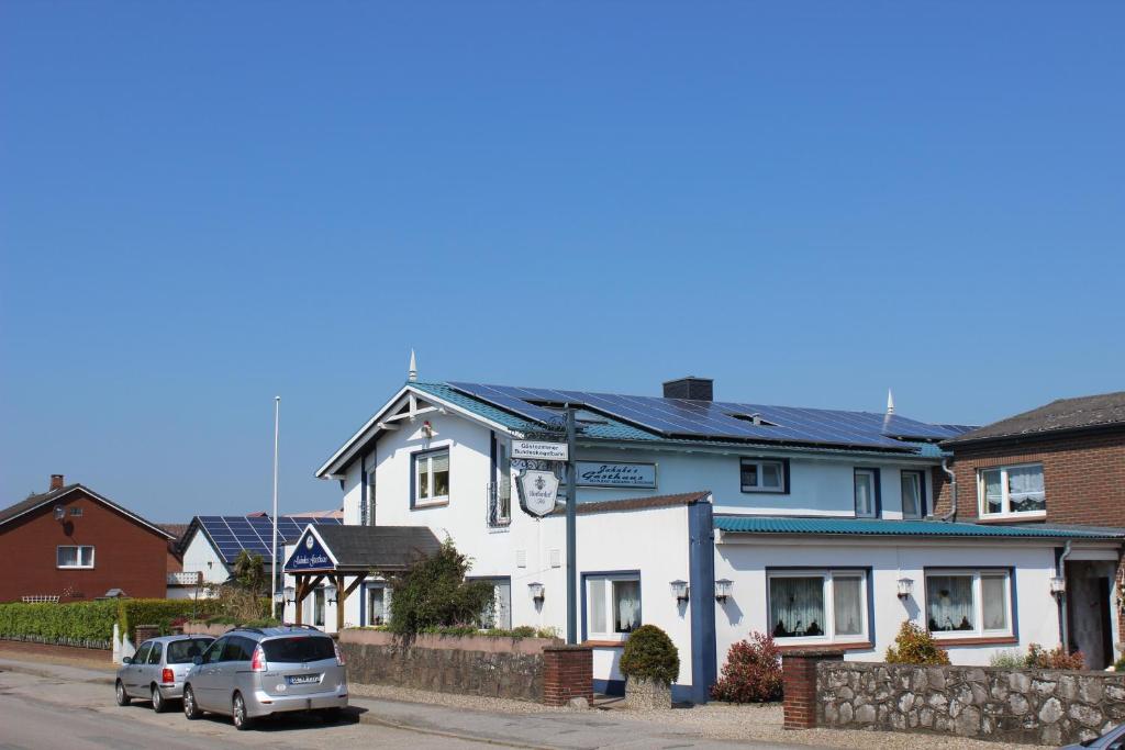 a white house with a car parked in front of it at Pension Jahnkes Gasthaus in Todesfelde