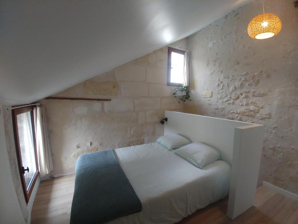 ein Schlafzimmer mit einem weißen Bett und einer Steinmauer in der Unterkunft Villandry centre Appartement duplex entièrement rénové, au calme in Villandry