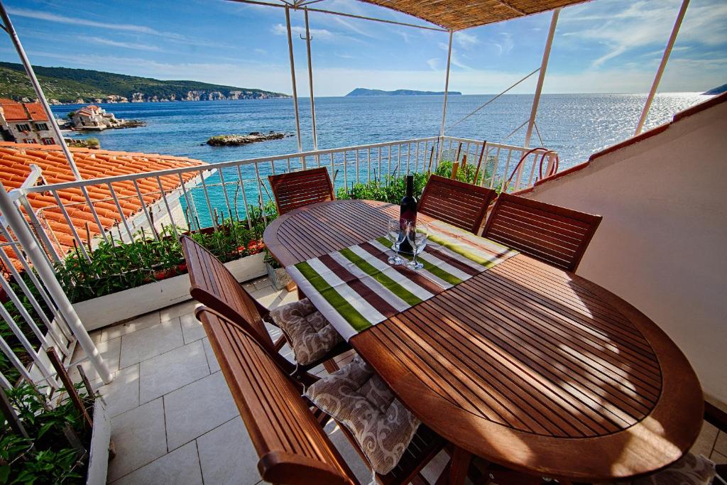 einen Holztisch auf einem Balkon mit Blick auf das Wasser in der Unterkunft Mira Sea Front Guesthouse in Komiža