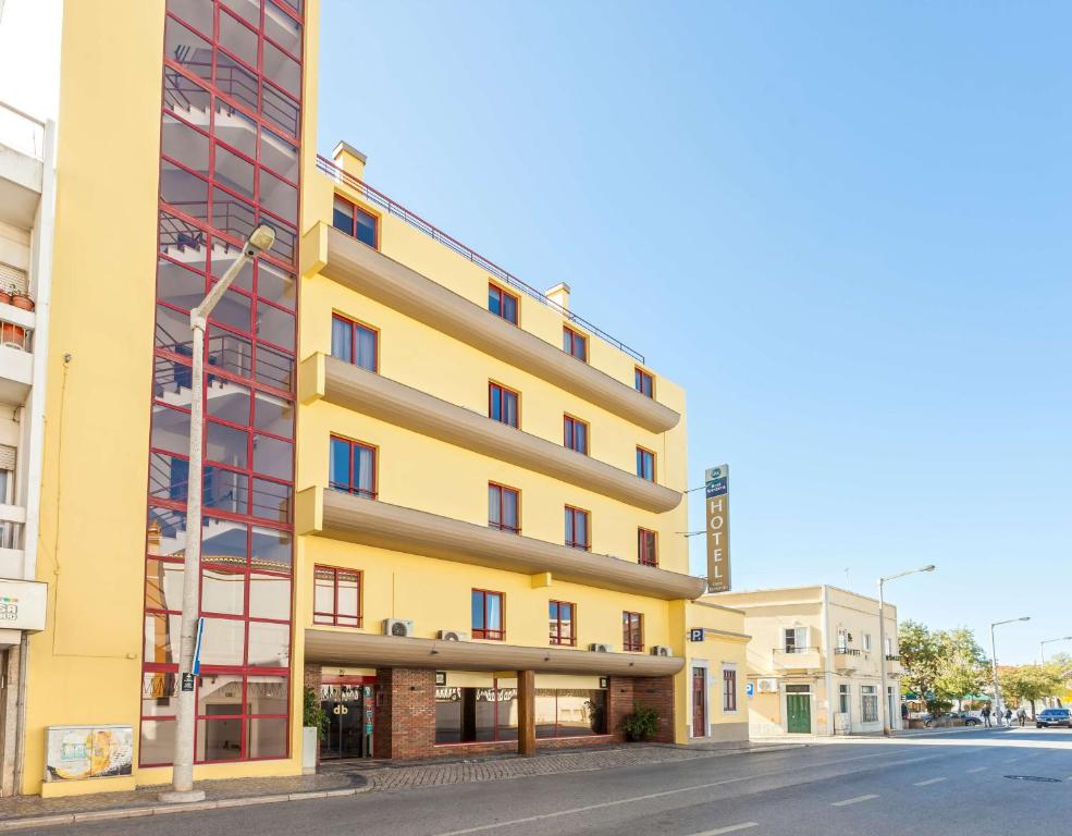 ein gelbes Gebäude an der Straßenseite in der Unterkunft Best Western Hotel Dom Bernardo in Faro