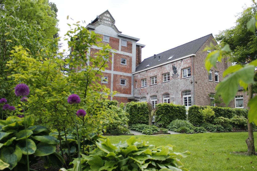a garden in front of a large brick building at Housing De Brouwerij in Westdorpe