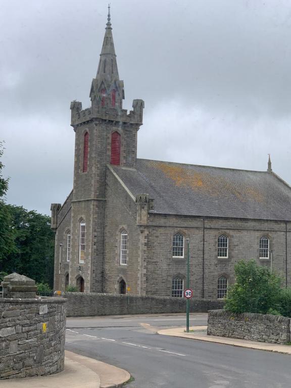 a large stone building with a tower on a street at Church view in Wick