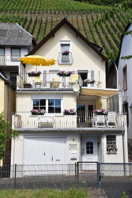 a white house with a balcony and an umbrella at Apartment Moselblick in Ürzig