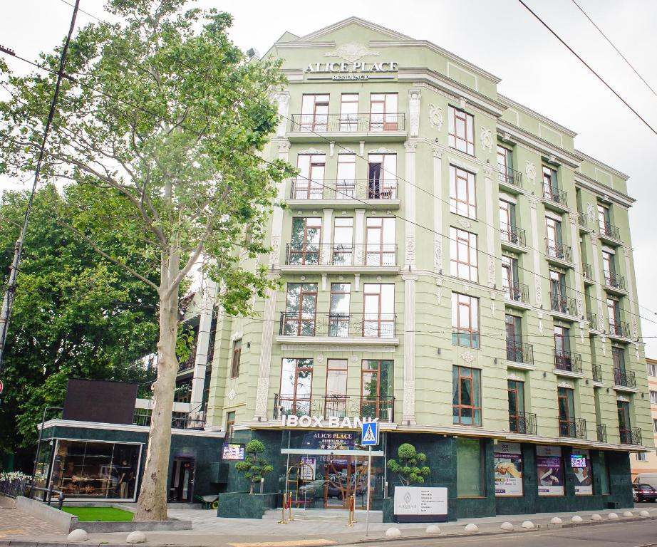 un grand bâtiment vert au coin d'une rue dans l'établissement Alice Place Hotel, à Odessa