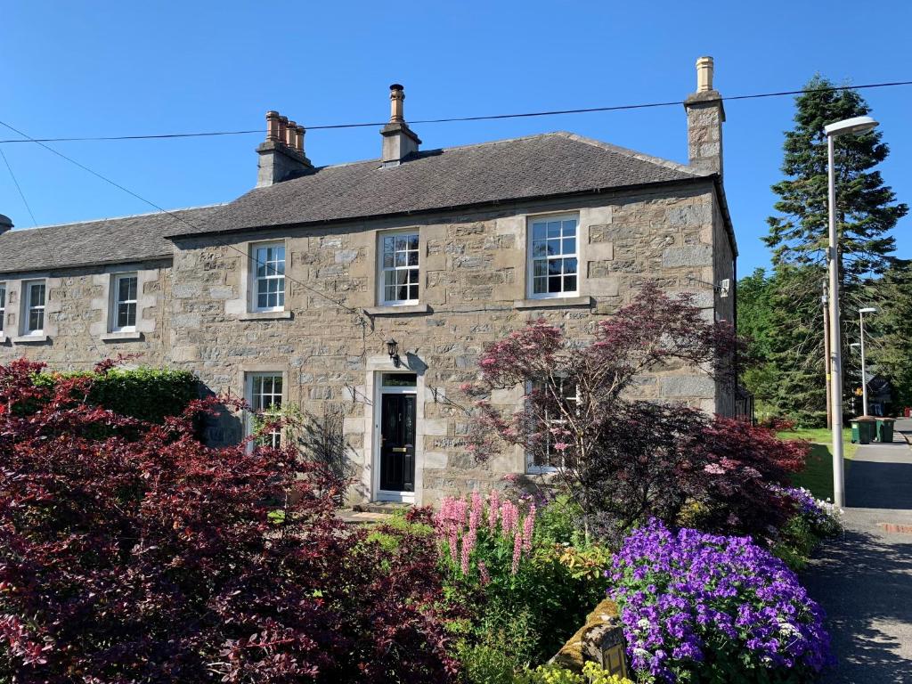 an old stone house with flowers in front of it at Immaculate 3 Bedroom House in Blair Atholl in Blair Atholl