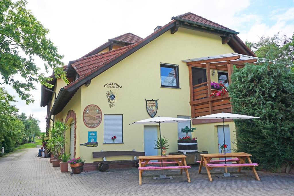 a building with tables and umbrellas in front of it at Winzerhof Spengler in Külsheim