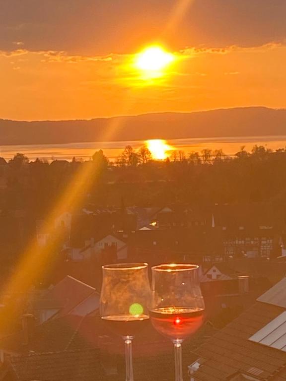 dois copos de vinho com o pôr-do-sol ao fundo em Penthouse - Sunset Dream em Uhldingen-Mühlhofen