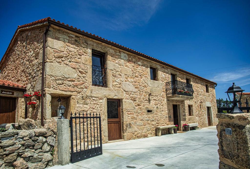 un edificio de piedra con una puerta y una valla en Casa Rural Costa Azul, en Camariñas