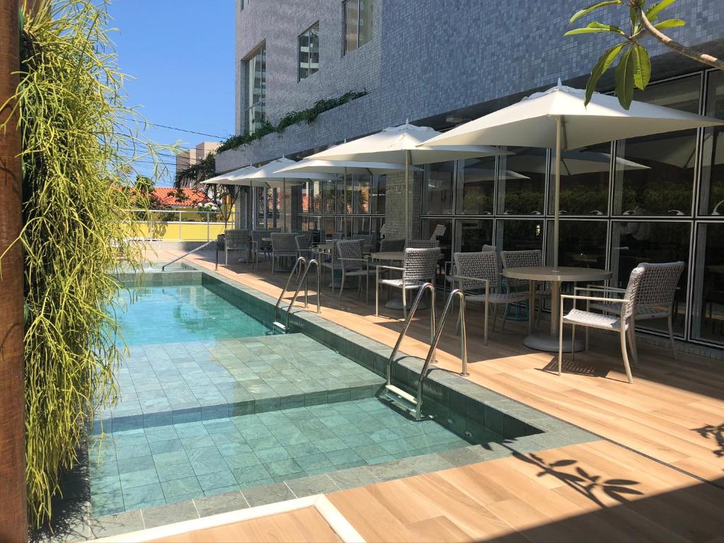 馬塞約的住宿－Flix Hotel，一个带桌椅和遮阳伞的游泳池