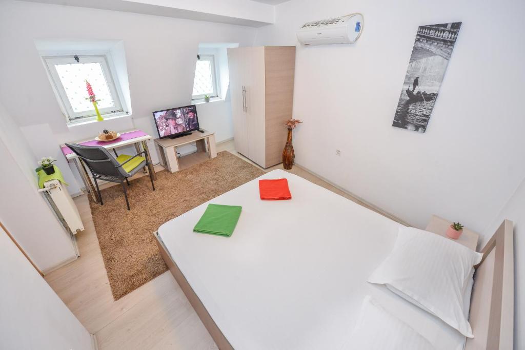 a small room with a white bed and a desk at Unirii Suites in Bucharest