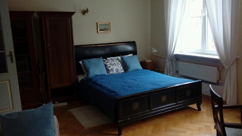 una camera da letto con un letto con lenzuola blu e una finestra di MINOGI a Danzica