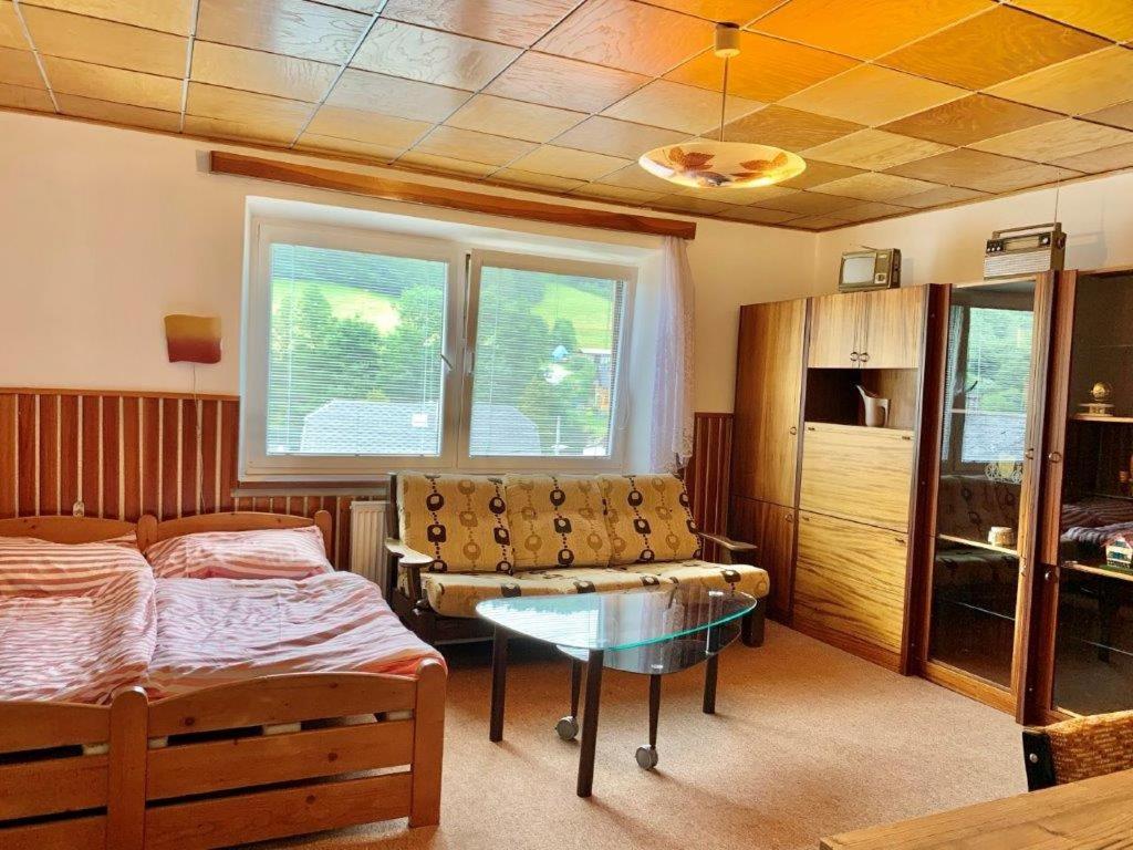 a bedroom with a bed and a table and a window at Apartmán Bušín in Busin