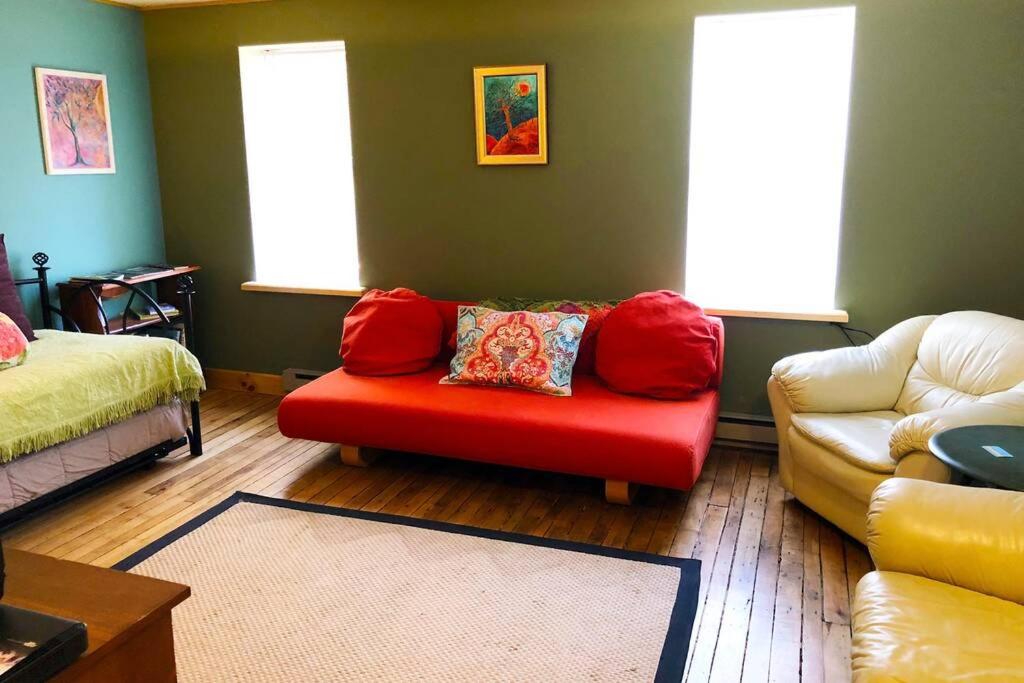 a living room with a red chair and a couch at Olga's Upstairs (Apartment near Cherry Springs State Park) in Coudersport