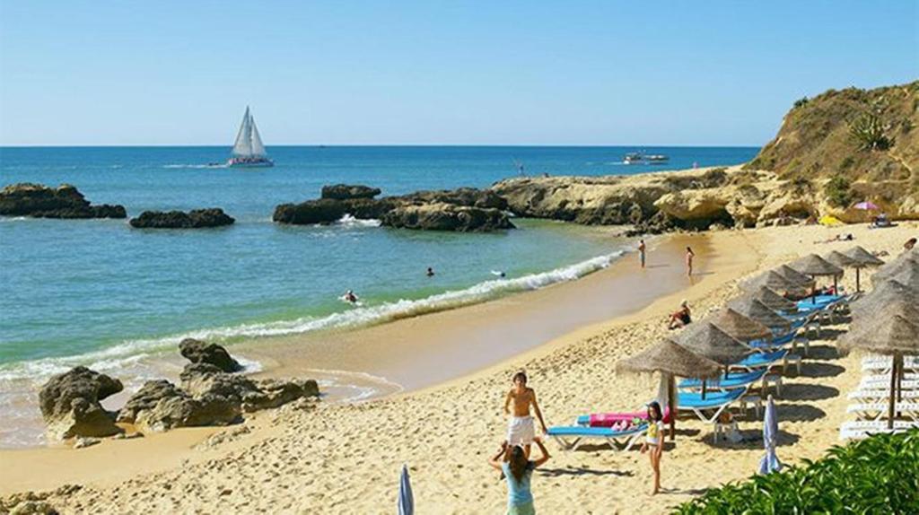 een strand met parasols en mensen die in de oceaan zwemmen bij Albufeira INN - Casa dos Aveiros - Dolamar 4A T1 in Albufeira